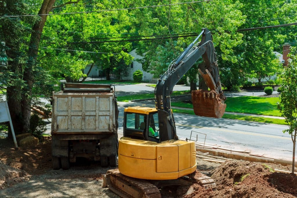 Yellow heavy duty digger working in excavation pit on background of residential complex